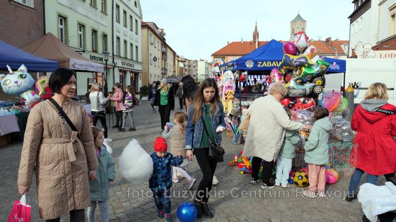 uczestnicy jarmarku, w tle kramy, ulica